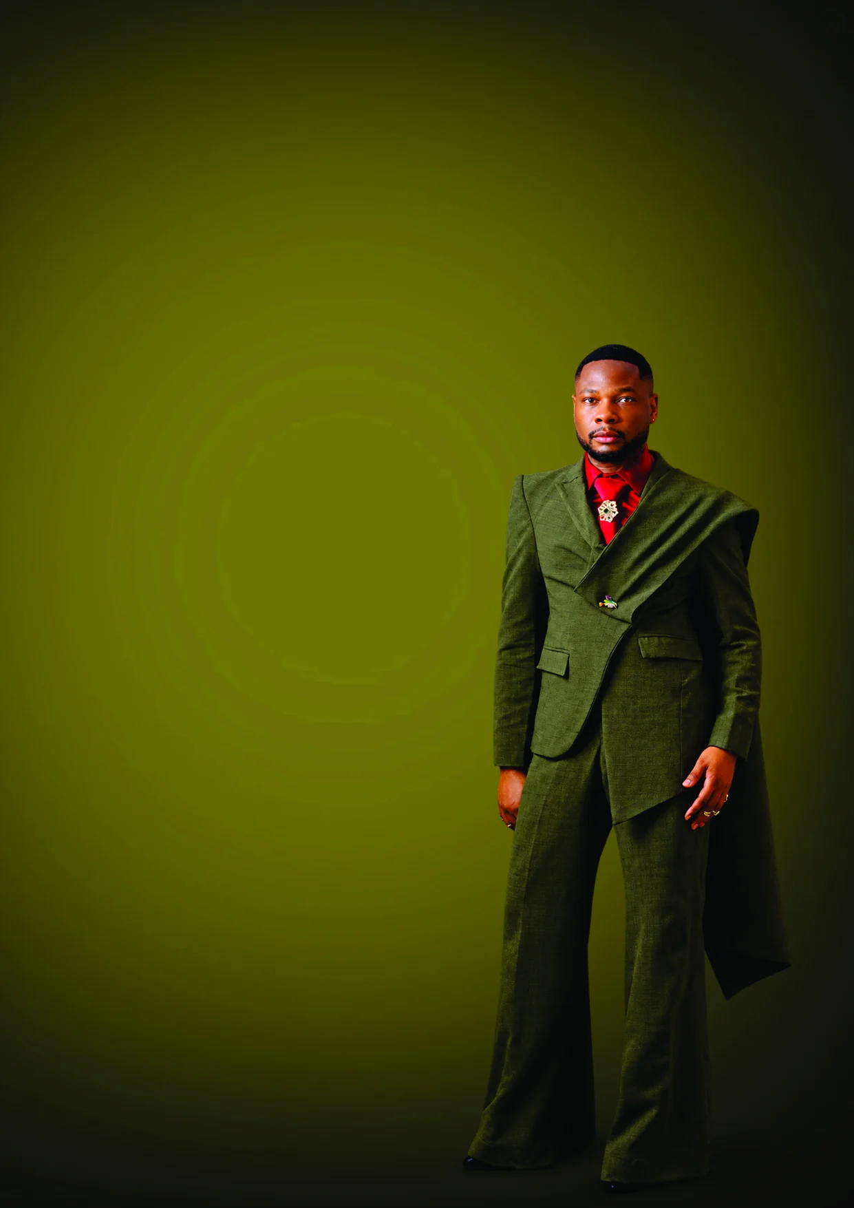 A man in a draped olive suit and red shirt