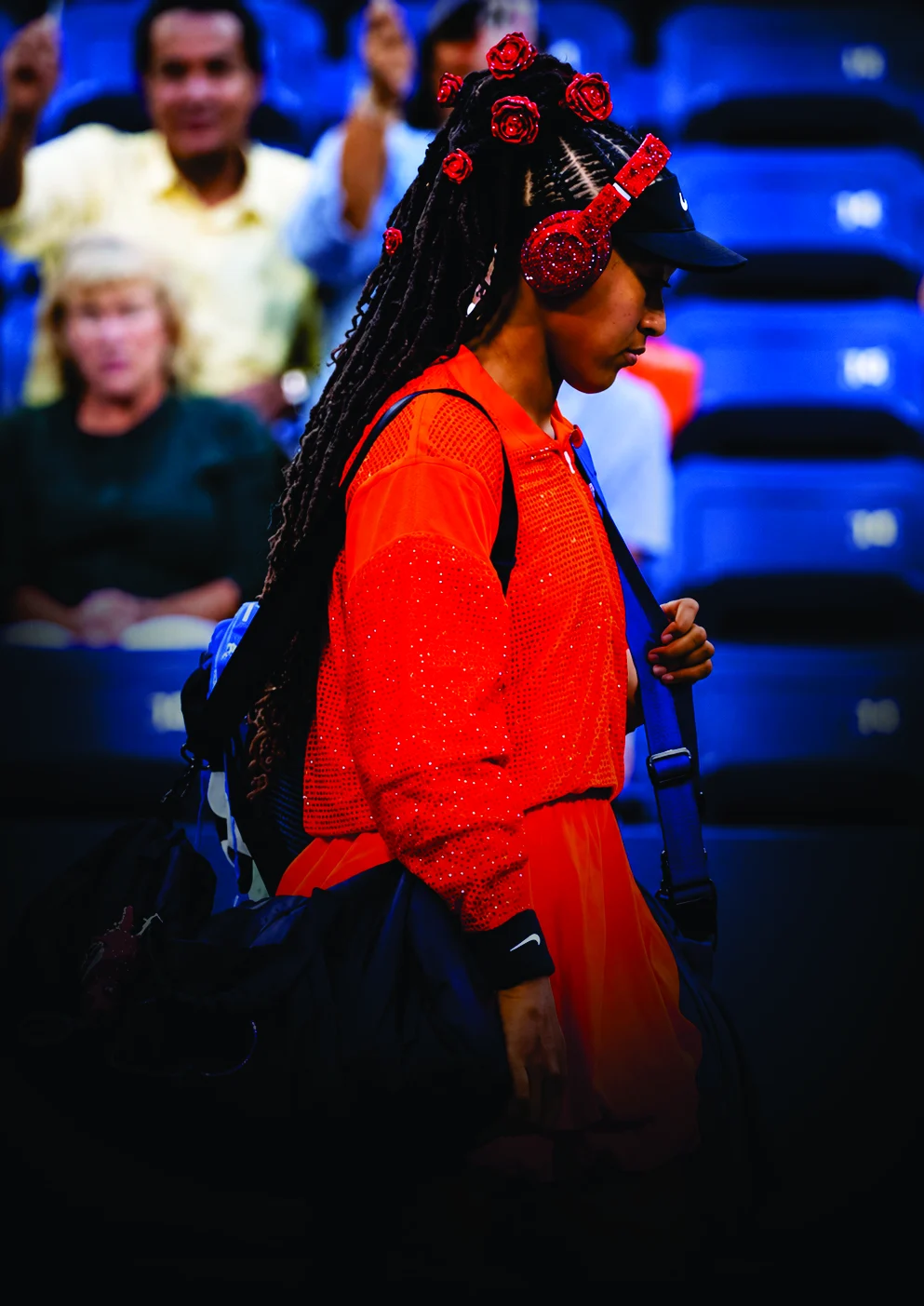 Naomi Osaka walking on court in red sequins with crystal-covered headphones