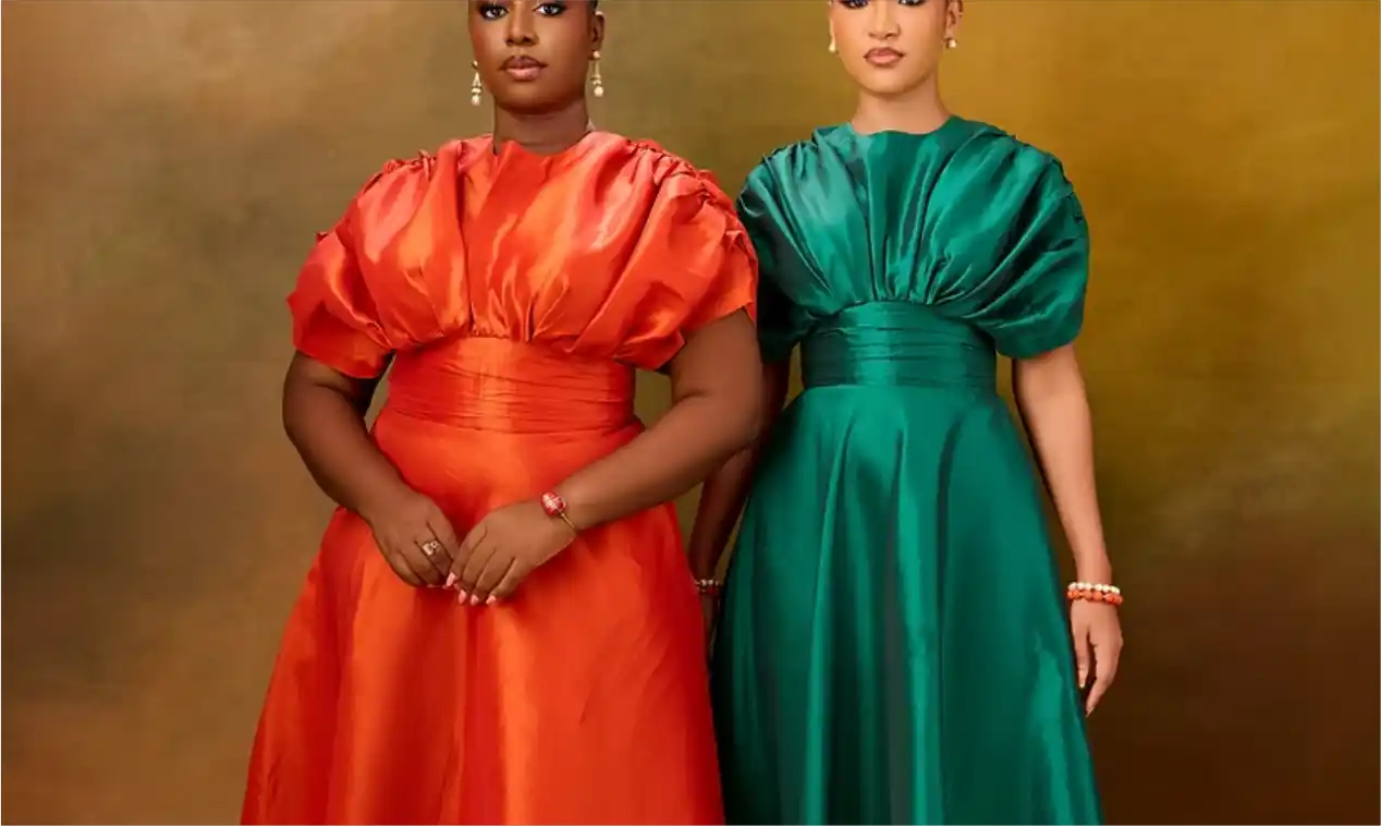 Two women in red and green satin balloon-sleeve gowns