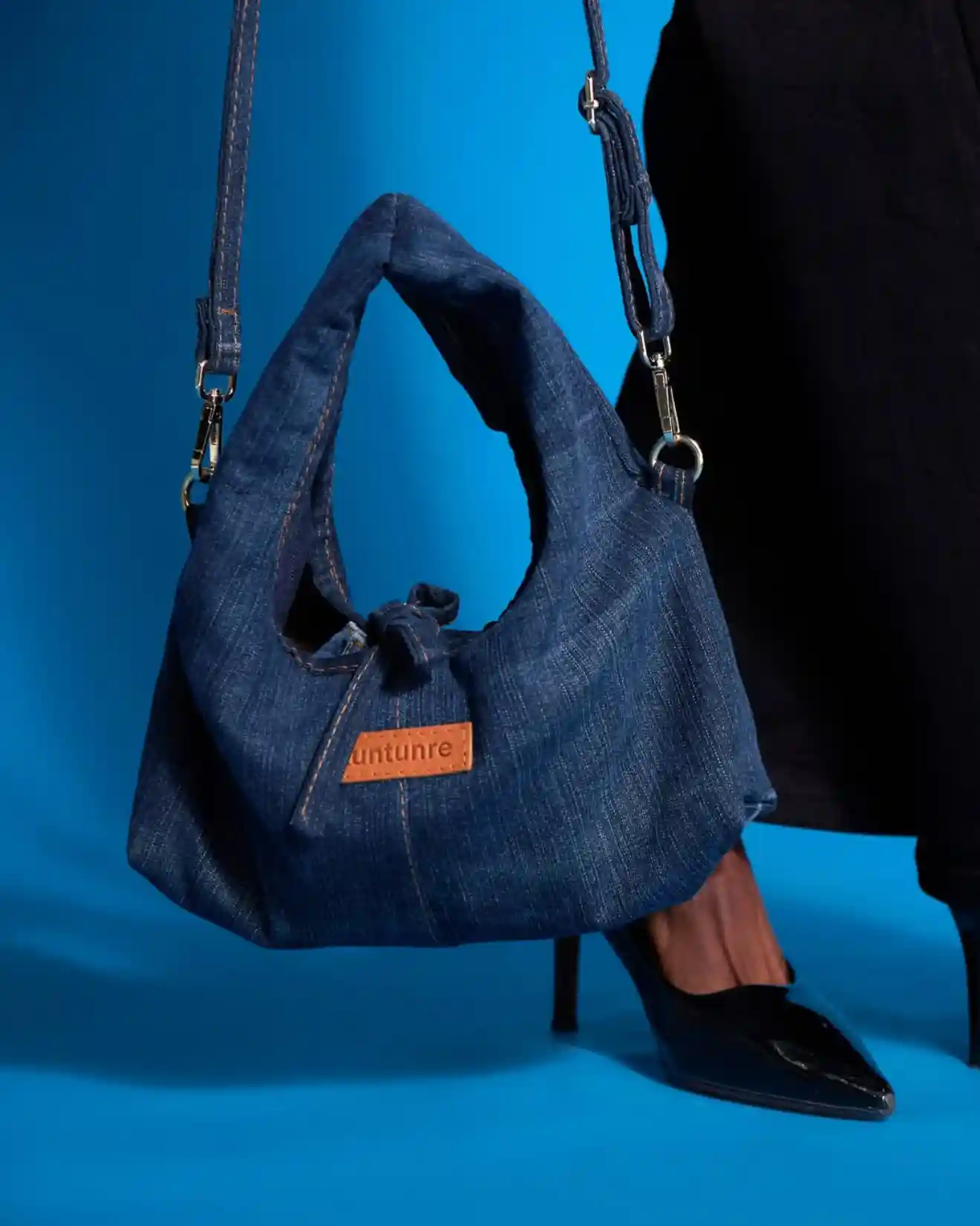 Tuntunre denim bag hanging against a blue background
