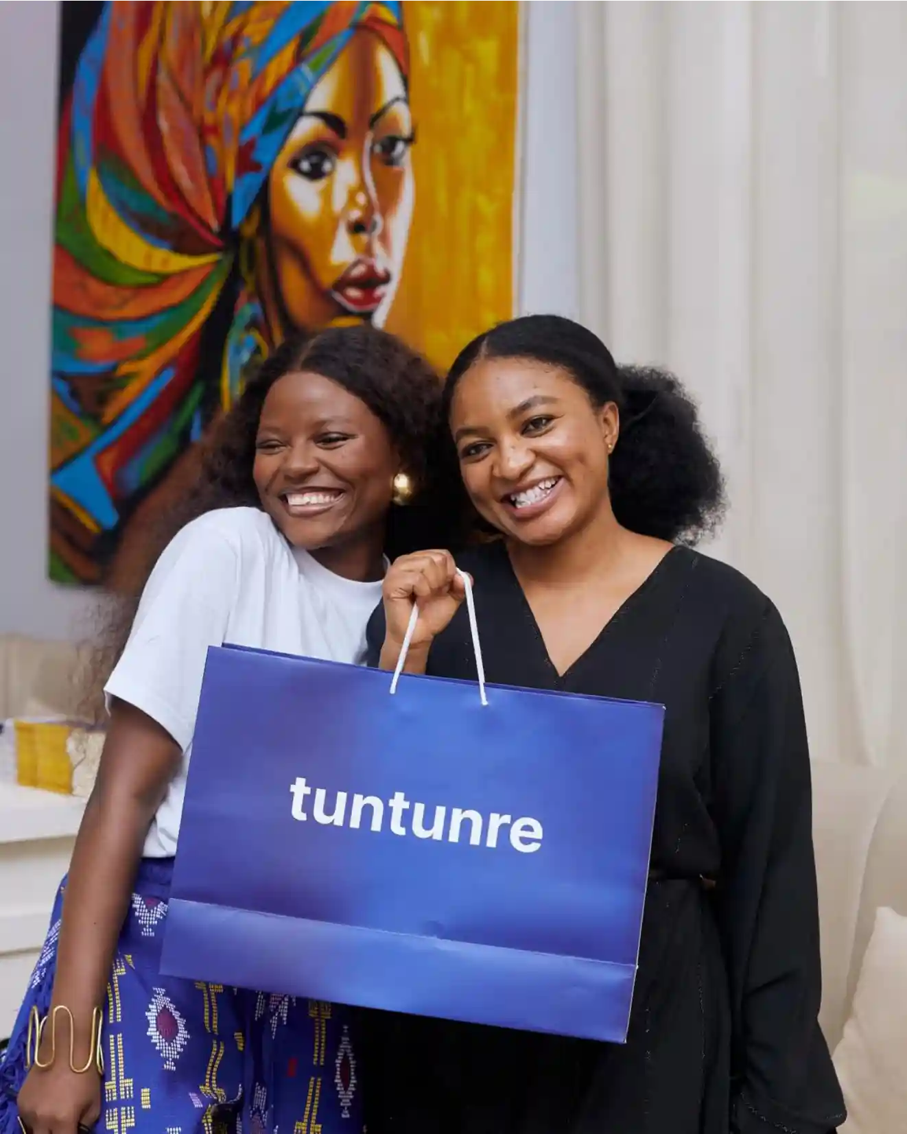 Two women smiling, one holding a blue Tuntunre shopping bag