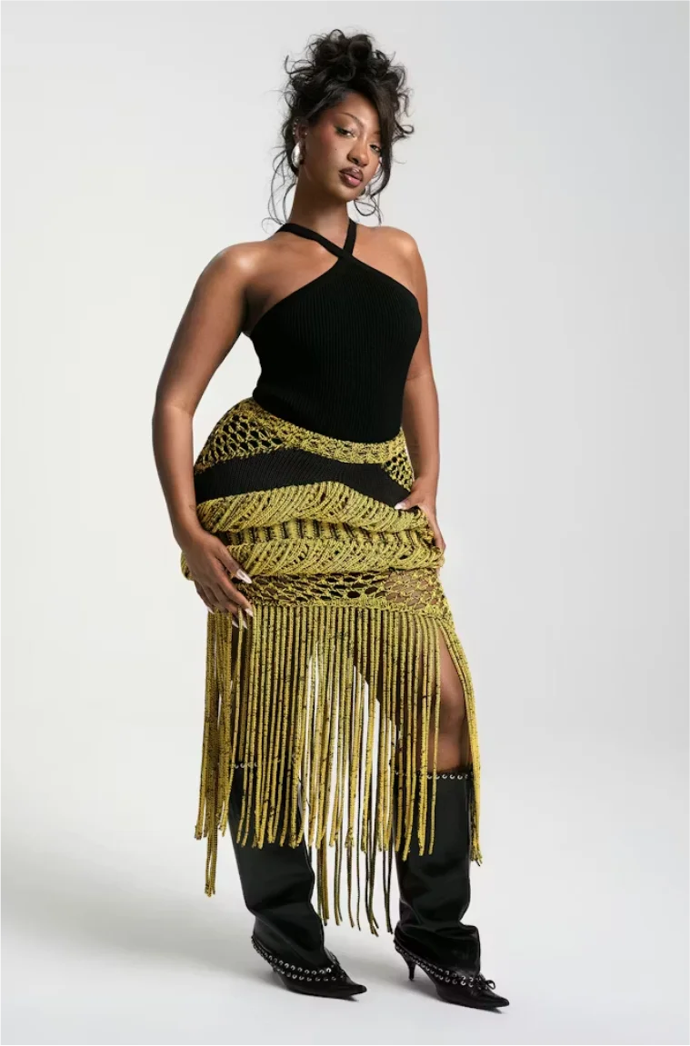 Tems in a black halter top with gold fringe skirt